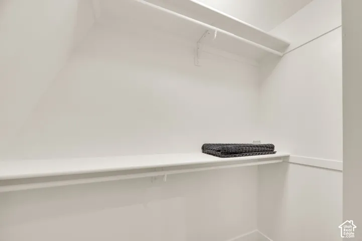 Corner closet featuring white shelving and a hanging rod