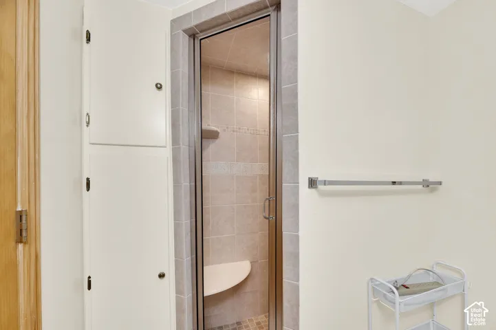 Glass-enclosed shower featuring tiled walls, a built-in bench, and a mosaic accent band
