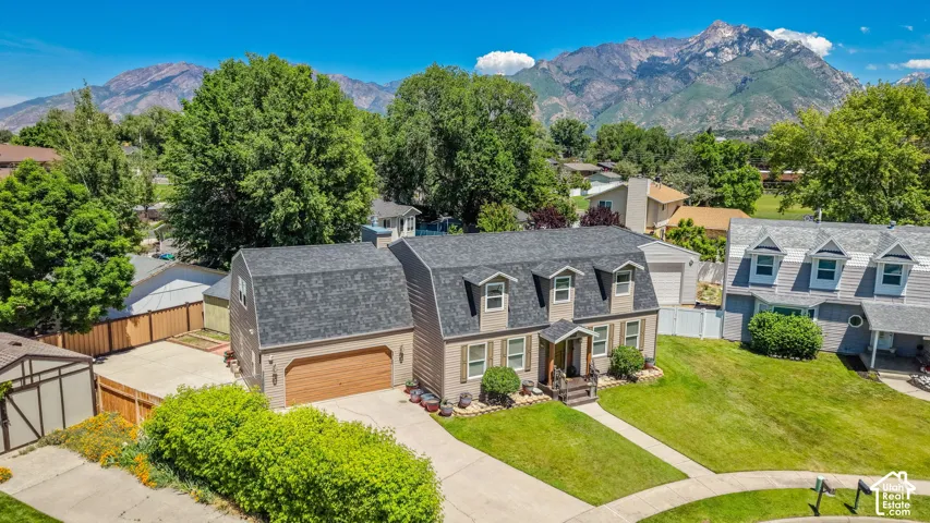 Two-story residence featuring dormer windows, a covered front entry, and a side-facing garage with a wood-finish door
