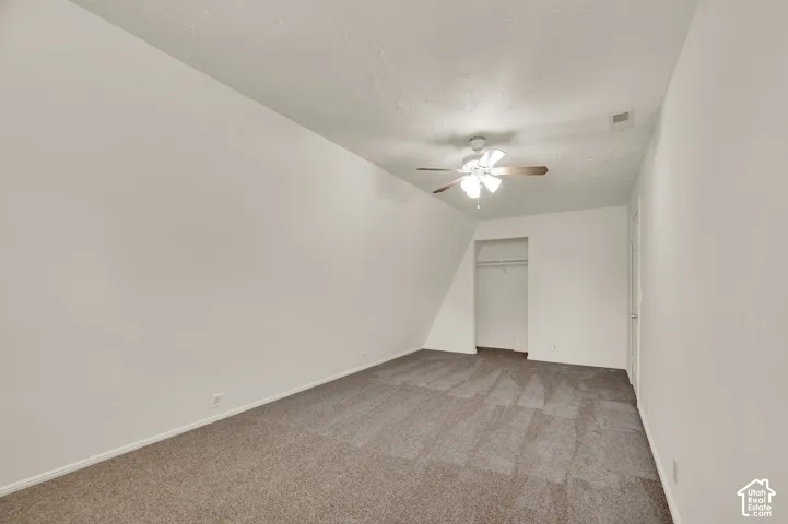 Carpeted interior space featuring white walls and a sloped ceiling