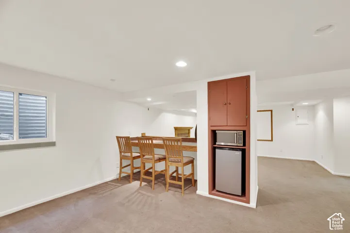 Lower-level space featuring a built-in bar with wood-finish countertop, recessed lighting, and carpeting