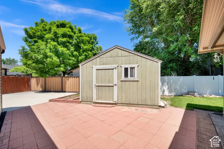 Expansive brick paver patio featuring a standalone storage shed with a window and a wood door
