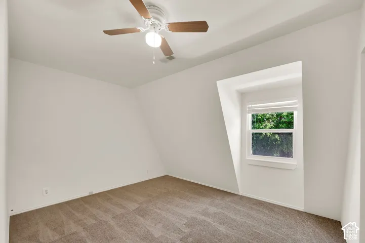 Dormer window with white blinds, neutral carpet flooring, and a ceiling fan with integrated lighting