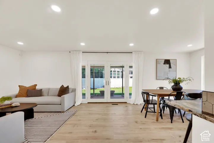 Open-concept living area featuring wood-finish flooring, recessed lighting, and patio access through glass French doors