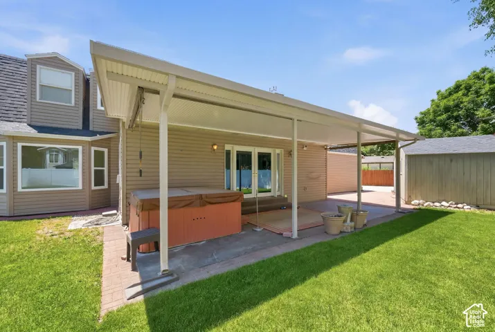 Expansive backyard featuring a covered patio, hot tub, and a detached storage shed