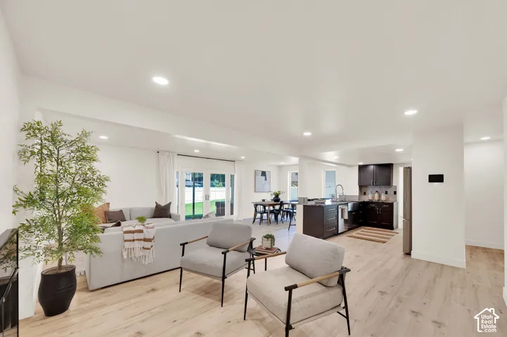 Open-concept living area featuring light wood-finish flooring, recessed lighting, and white walls