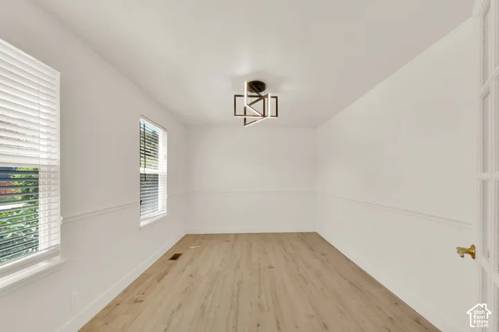 Bright interior space featuring light wood-finish flooring, white walls, and decorative chair rail molding