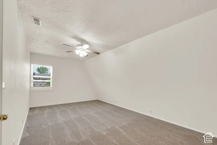 Carpeted room featuring a ceiling fan with integrated lighting, a window with horizontal blinds, and a neutral color palette
