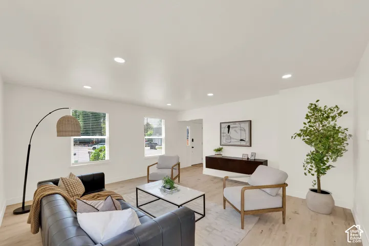 Bright living area featuring light wood-finish flooring, recessed lighting, and white walls