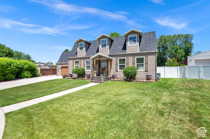 Cape Cod style exterior with dormer windows and a dark shingle roof