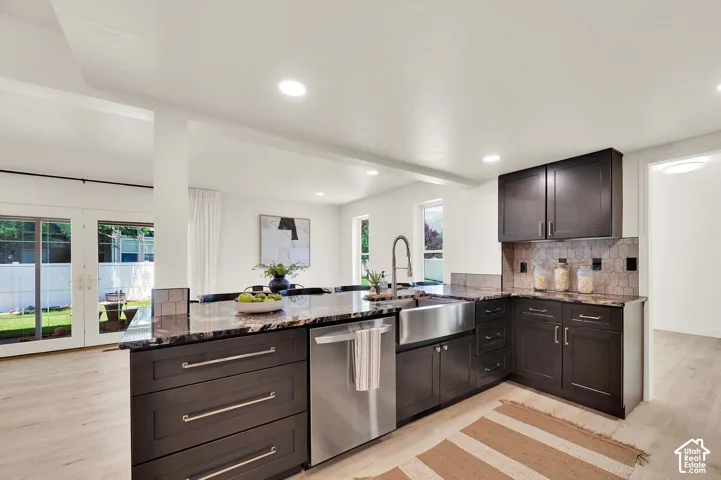 Open-concept kitchen featuring dark wood cabinetry, granite countertops, and a farmhouse-style sink