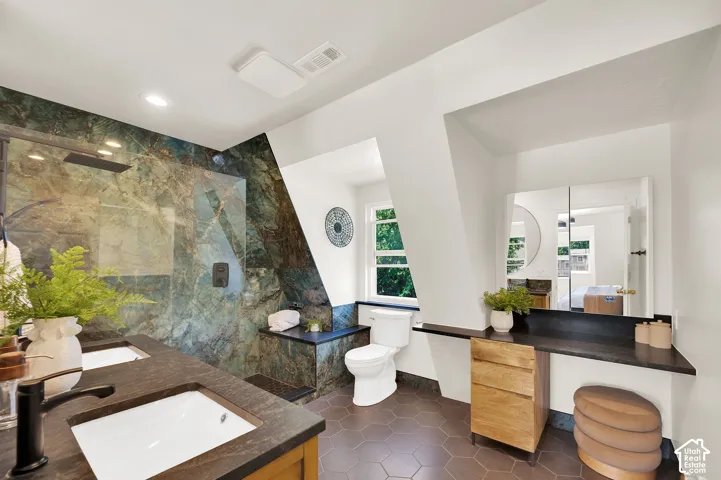 Spacious bathroom featuring a double vanity with integrated sinks, a walk-in shower with a glass enclosure and rain showerhead, a built-in bench, and a dedicated vanity area with storage