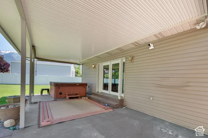 Covered patio featuring a solid roof structure, concrete flooring, and direct access through a set of French doors