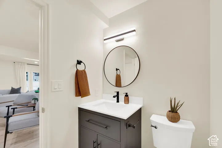 Bathroom featuring a dark gray vanity with integrated sink, white countertop, round wall-mounted mirror, and black matte faucet