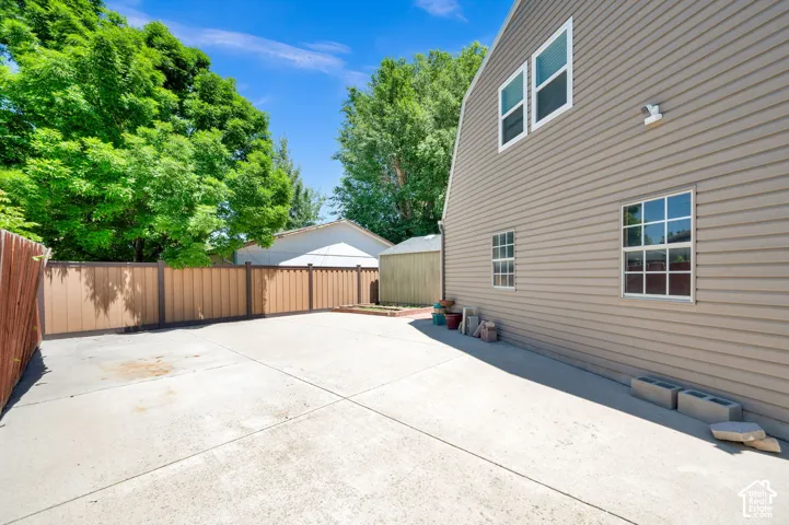 Paved concrete yard with a two-tone privacy fence, featuring vertical siding and multiple windows