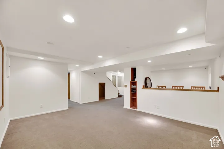 Expansive lower level featuring neutral carpeting, recessed lighting, white painted walls, and built-in shelving