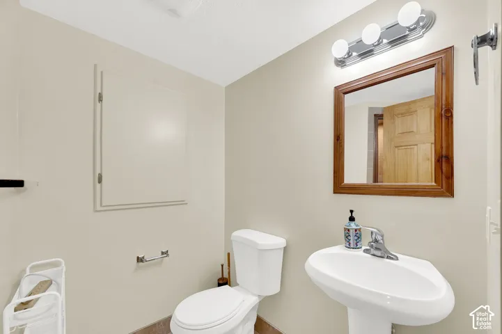 Bathroom featuring a pedestal sink, a wood-framed mirror, and a three-light vanity fixture