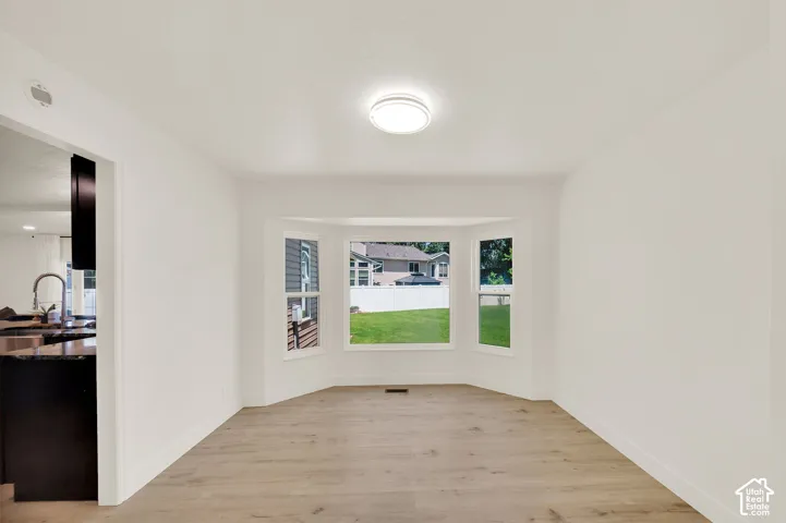 Bright interior space featuring a bay window, wood-finish flooring, white baseboards, and a flush mount ceiling light