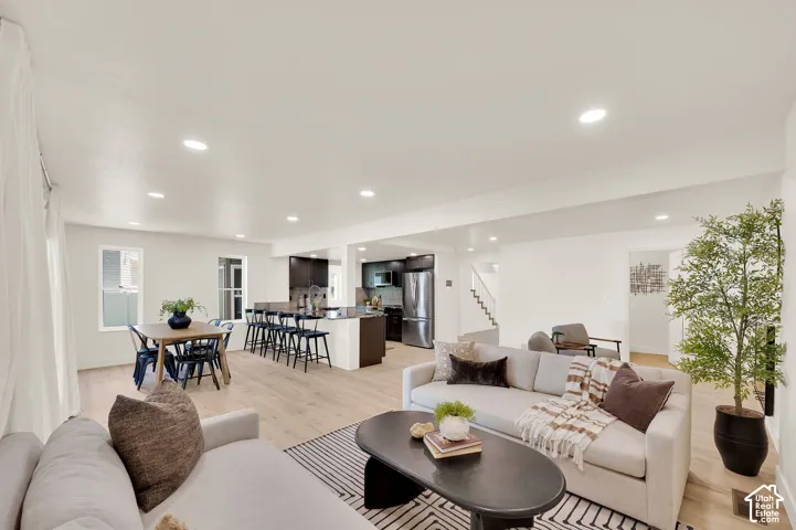 Open-concept living space featuring wood-finish flooring, recessed lighting, and white walls