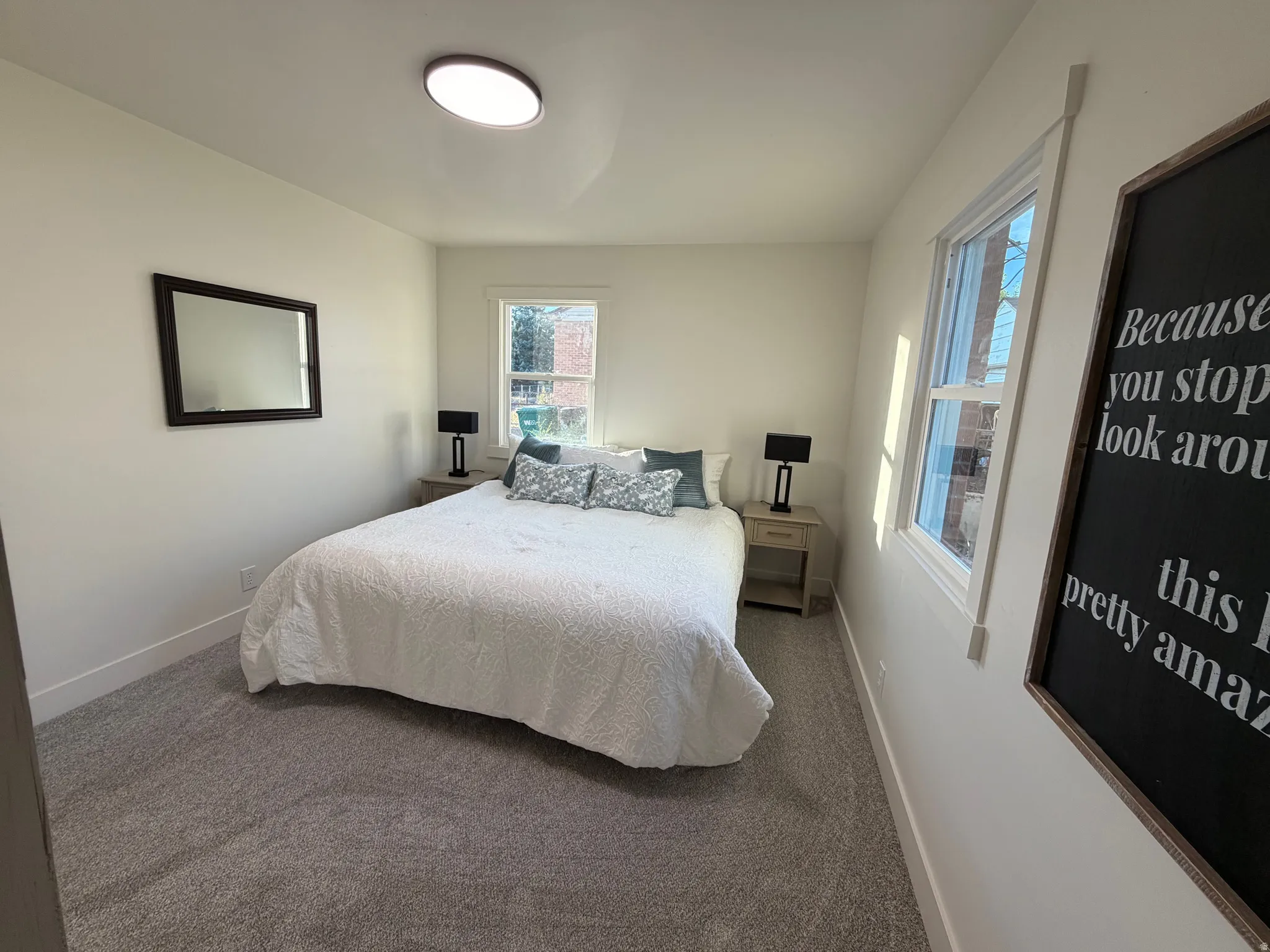Carpeted bedroom with neutral wall tones and a circular flush-mount ceiling light