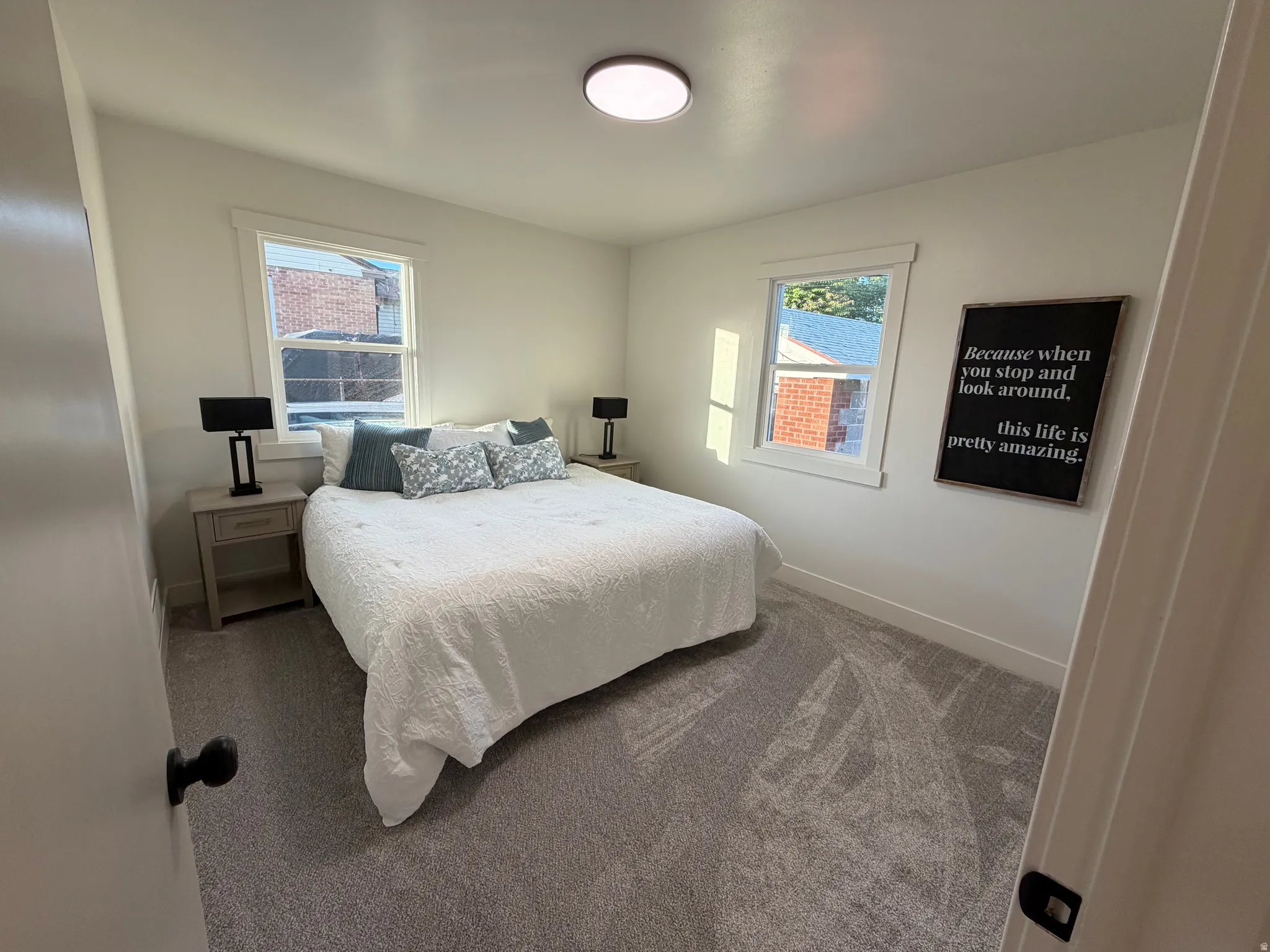 Room featuring two windows, neutral wall tones, and gray carpeting