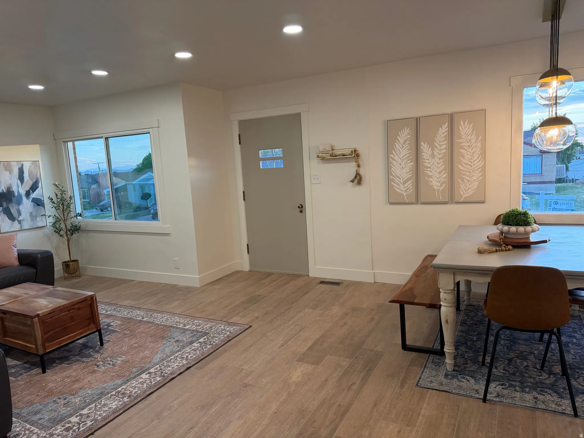 Open-concept living space featuring wood-finish flooring, recessed lighting, and a front entry door with privacy glass