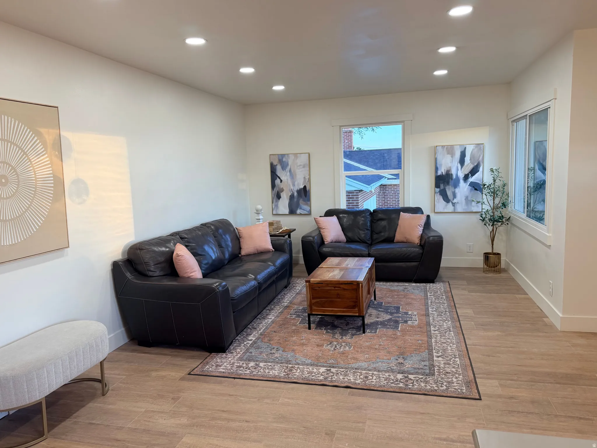 Spacious living area featuring light-toned walls, recessed lighting, wood-finish flooring, and multiple windows