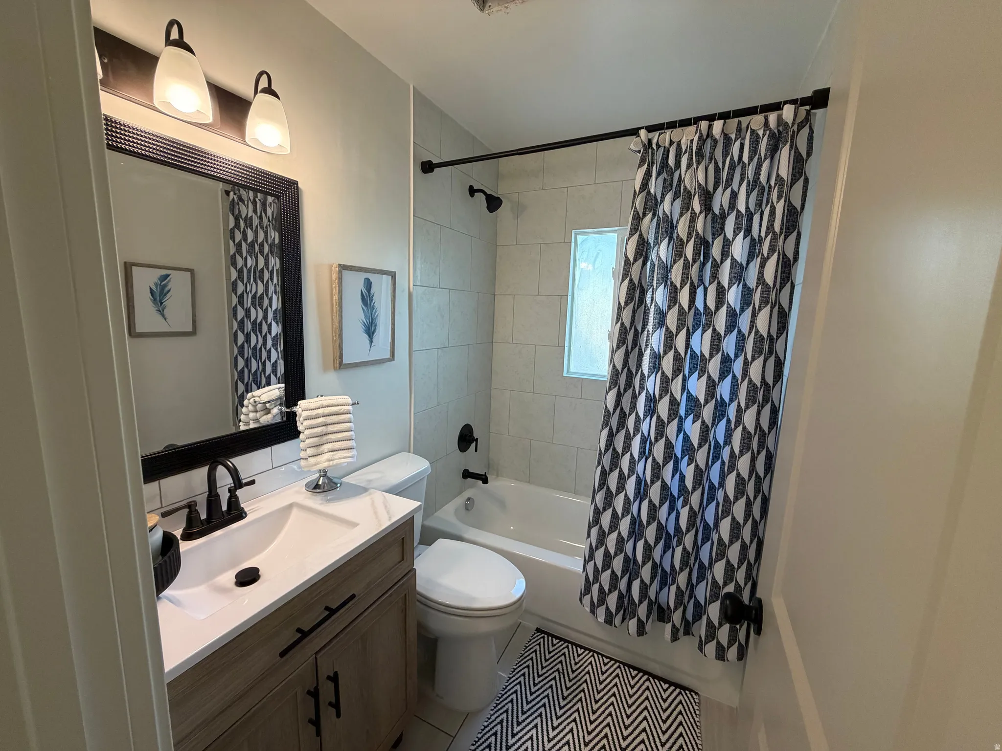 Bathroom featuring a vanity with a light wood-finish cabinet, white countertop, and dark-finish hardware
