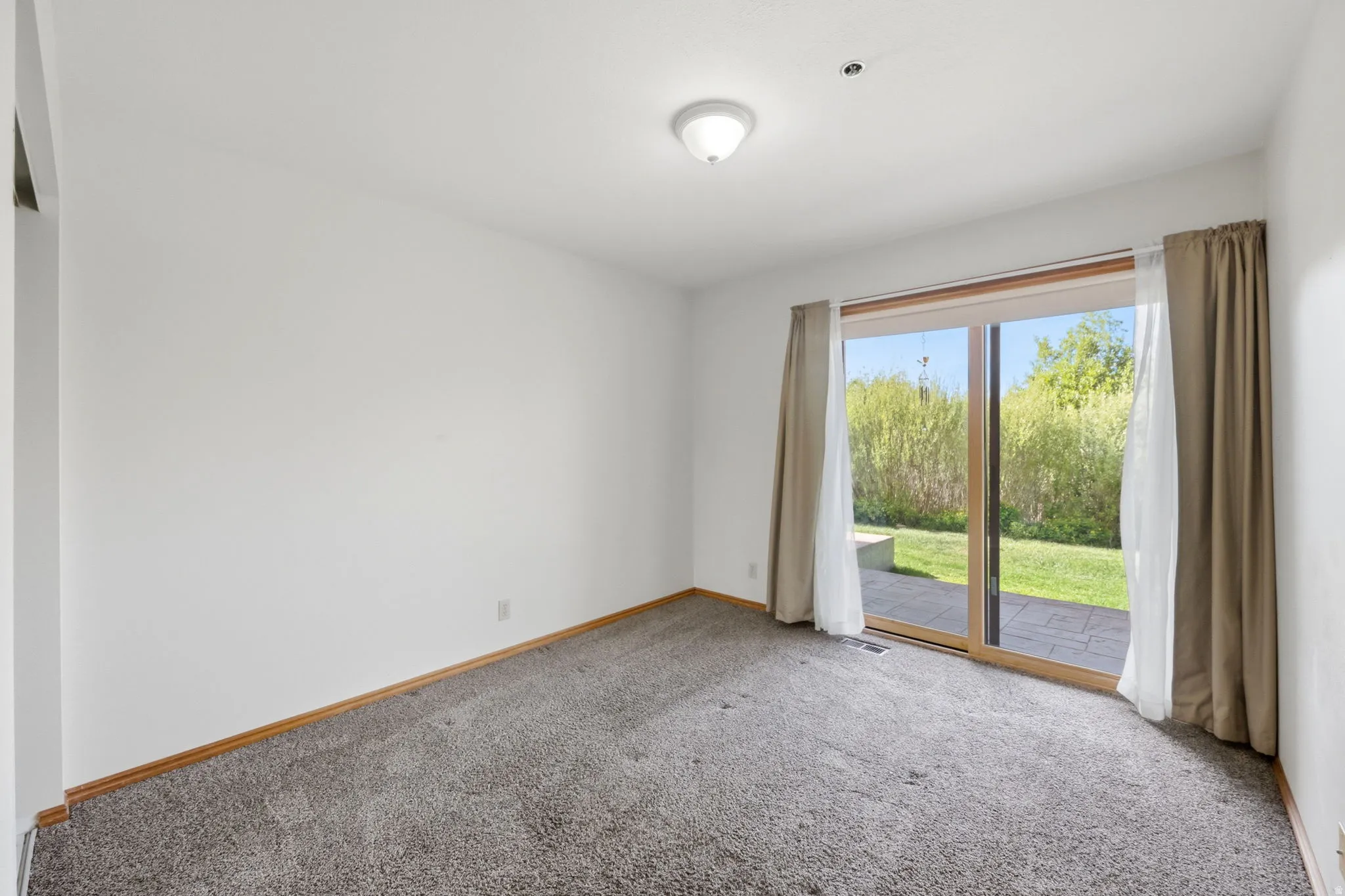 Carpeted room featuring a ceiling-mounted light fixture, white walls, and wood-finish baseboards