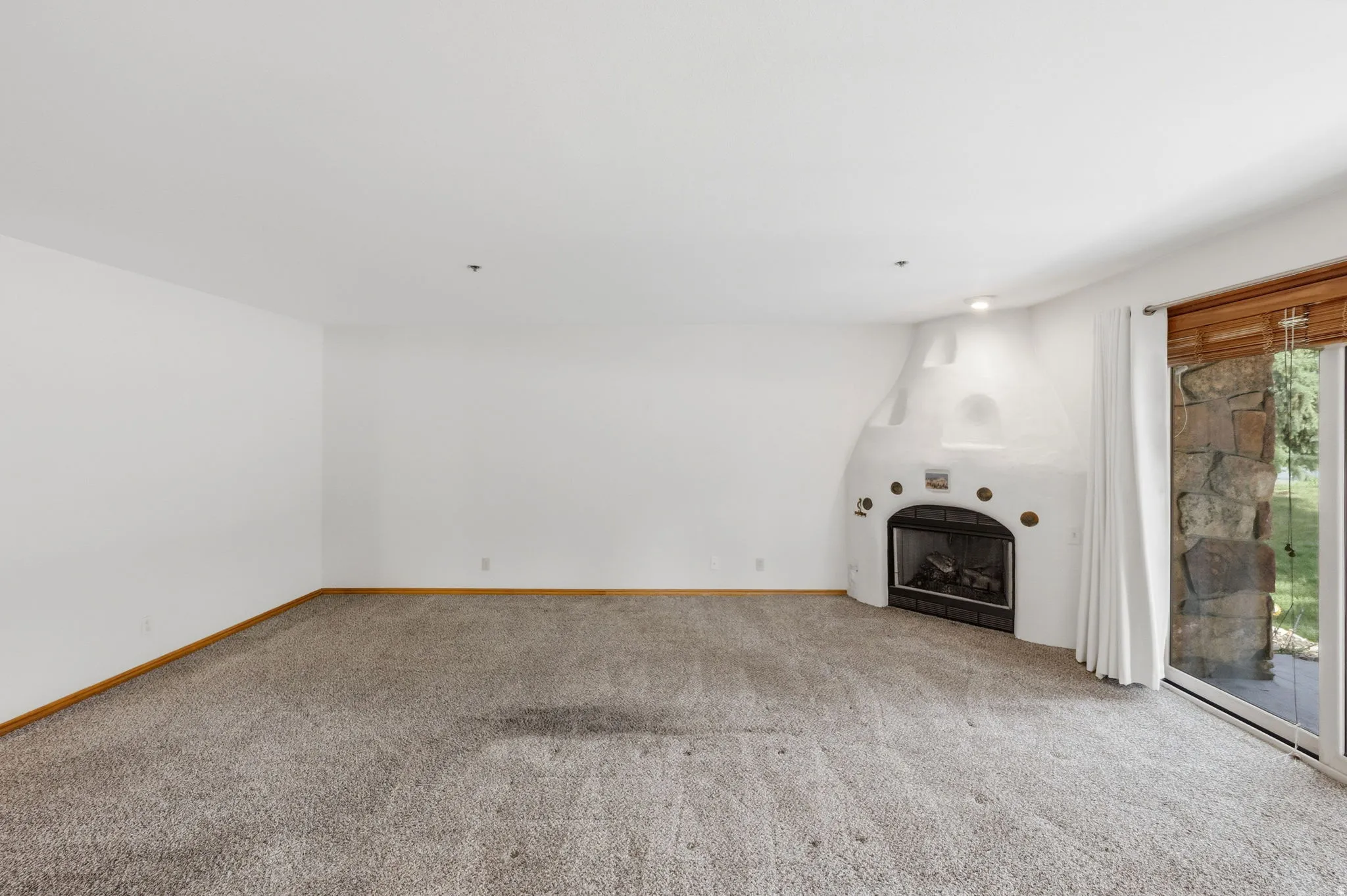 Spacious living area featuring a corner kiva-style fireplace with a black insert, an overhead recessed light, and a sliding glass door