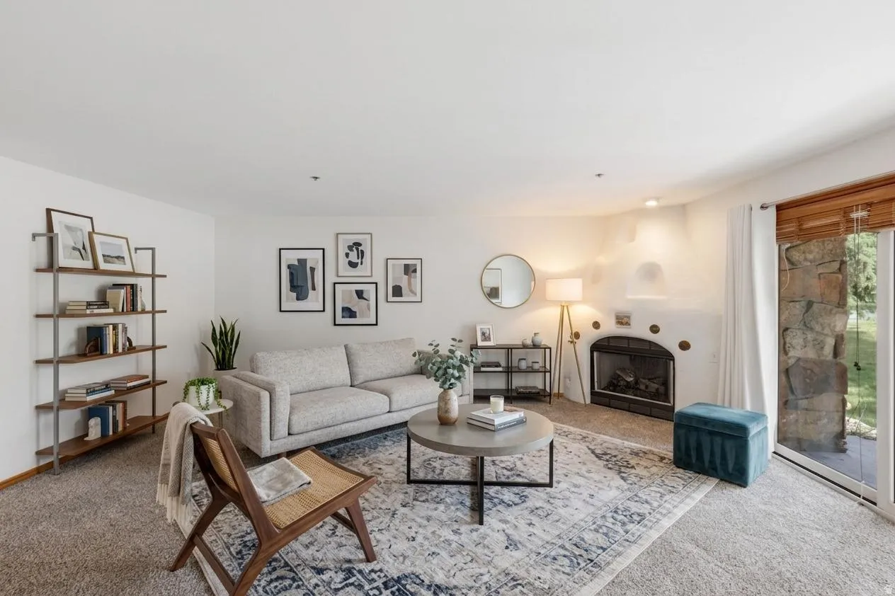 VIRTUAL  RENDERING: Spacious living area featuring a built-in fireplace, sliding glass door, and neutral carpeting