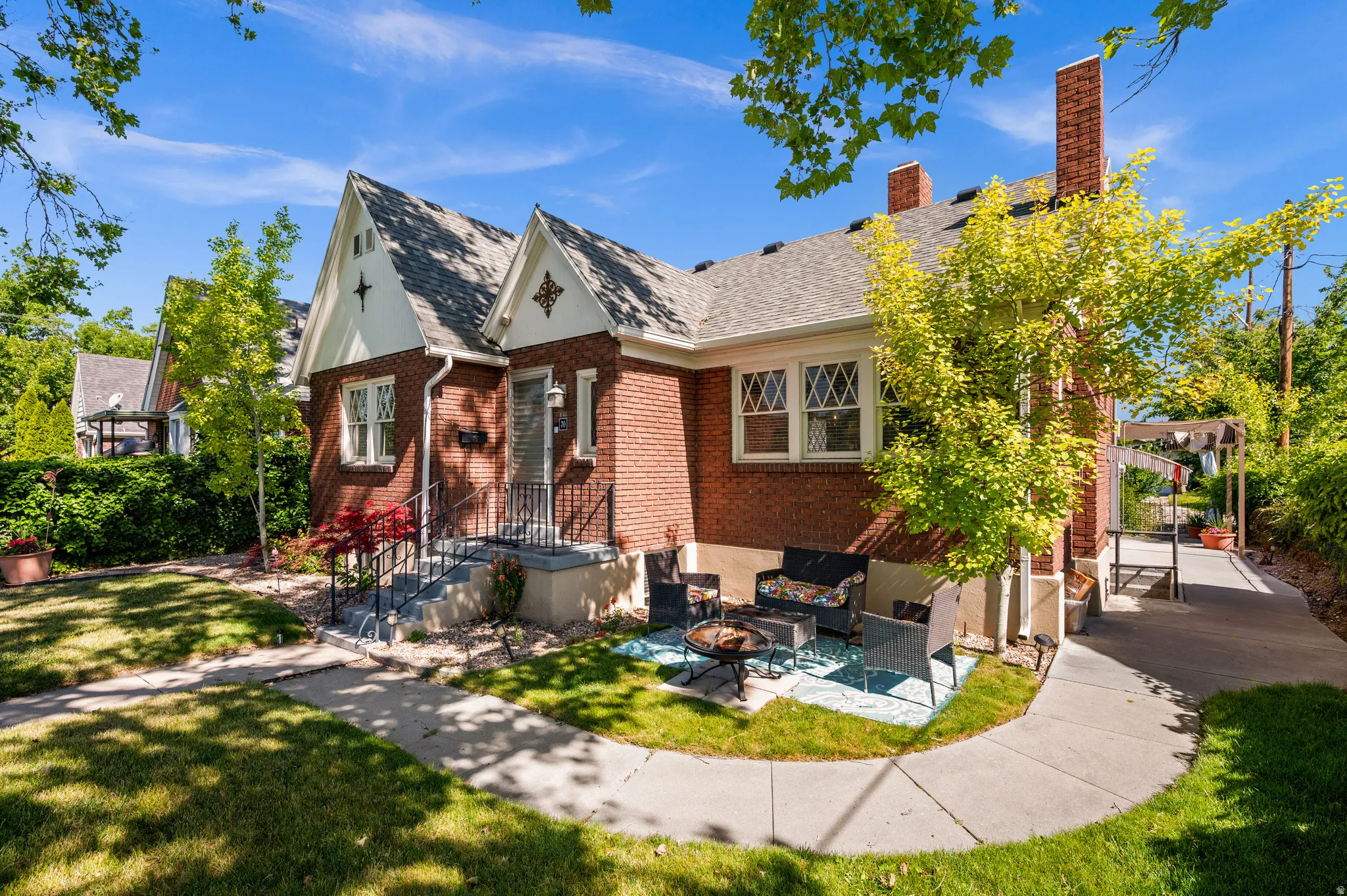 Brick exterior with a peaked roofline, decorative gables, a front entry with wrought iron railing, and a side patio