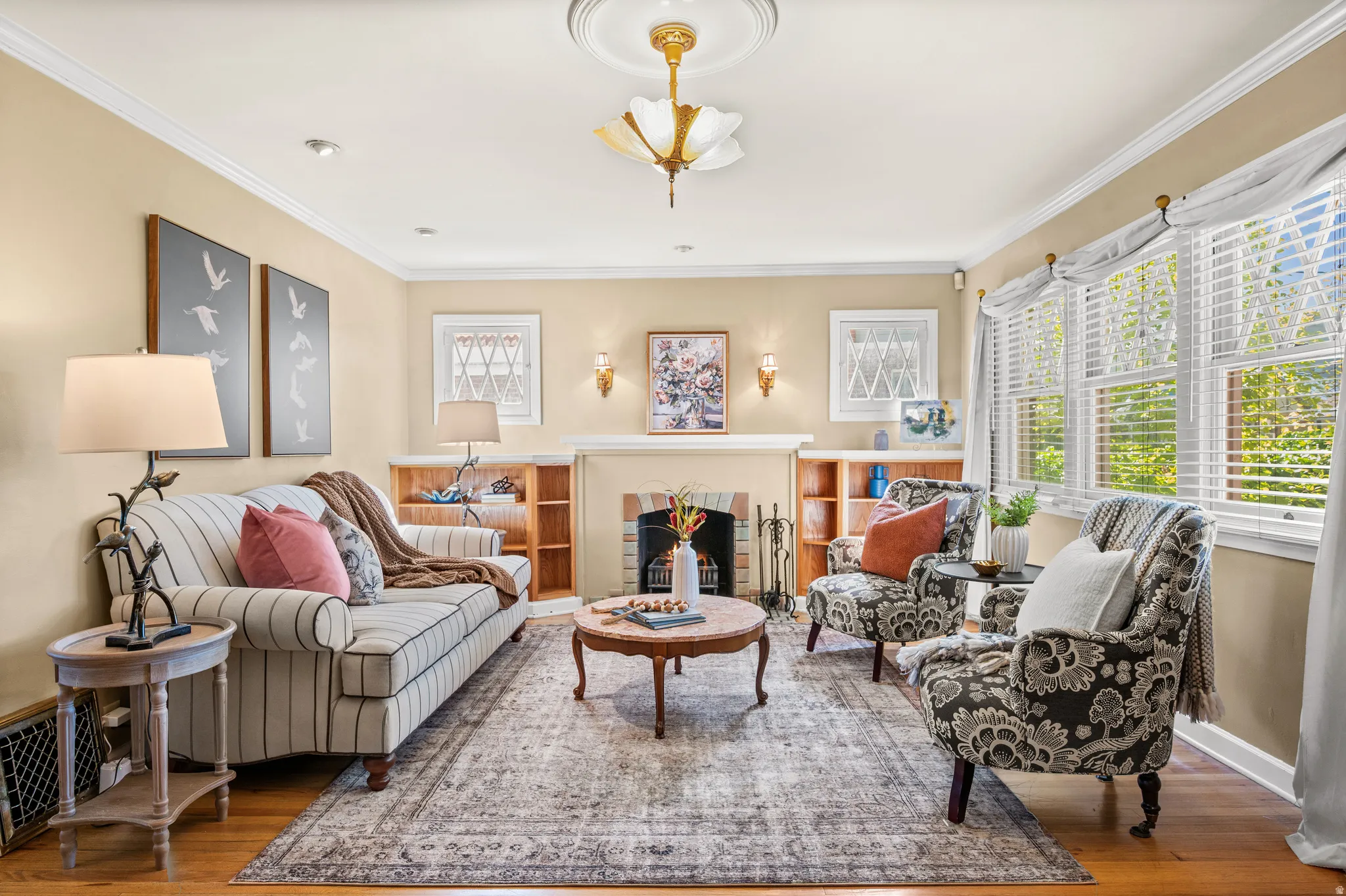 Living area featuring hardwood flooring, crown molding, and a central fireplace with a mantel