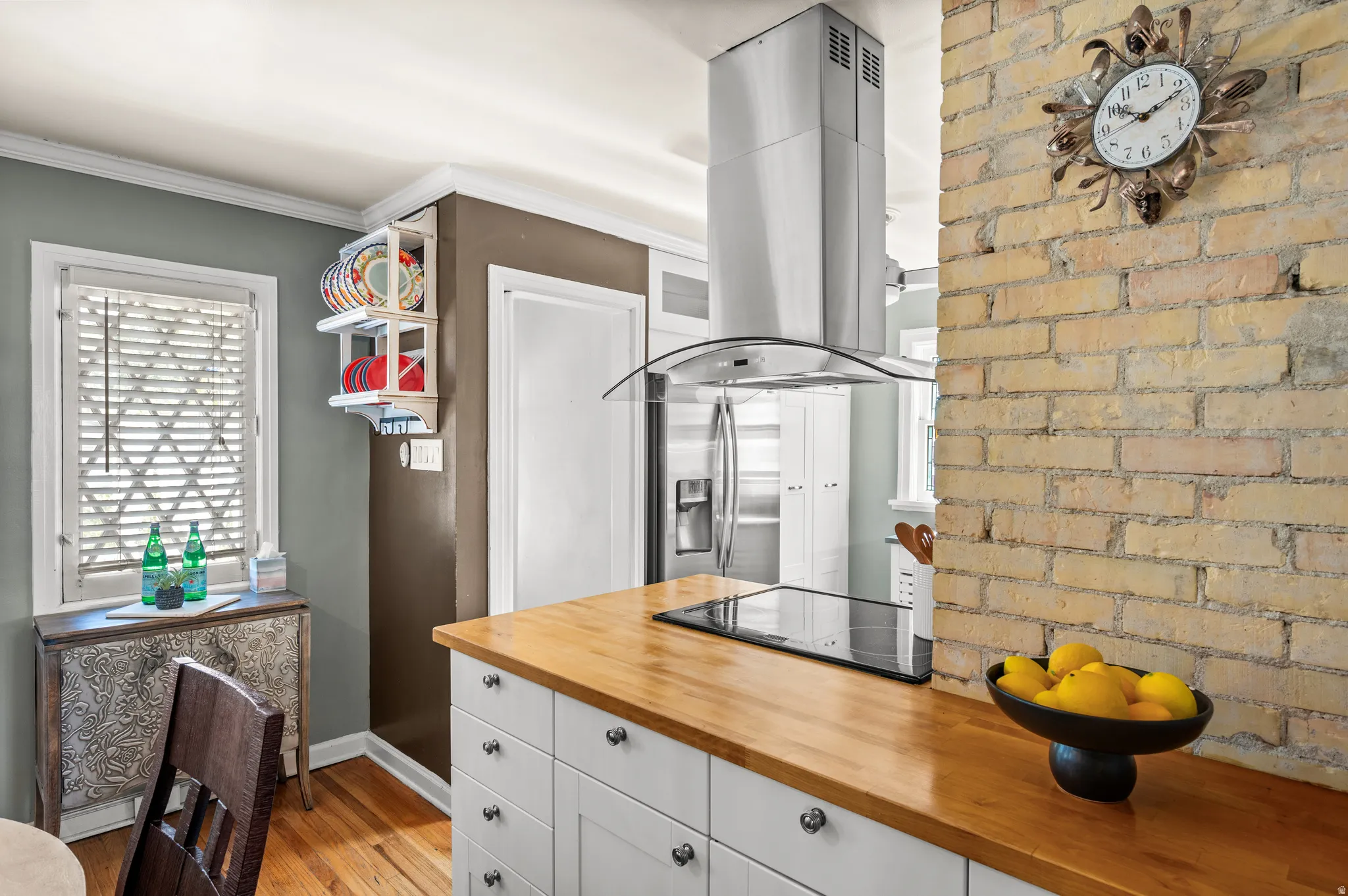 Kitchen featuring a stainless steel range hood, built-in cooktop, and wood-finish countertops