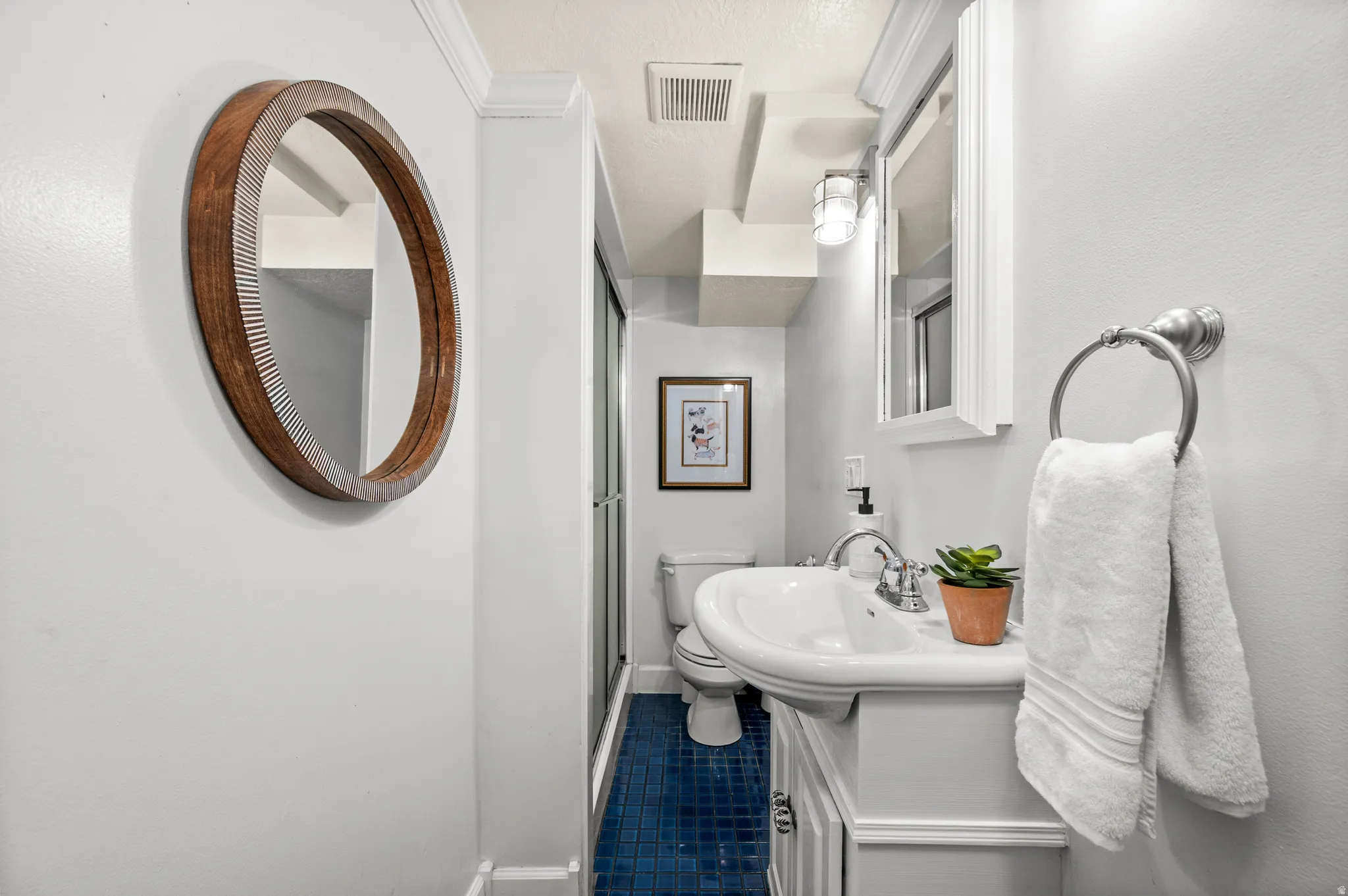 Pedestal sink with chrome fixtures and white cabinetry