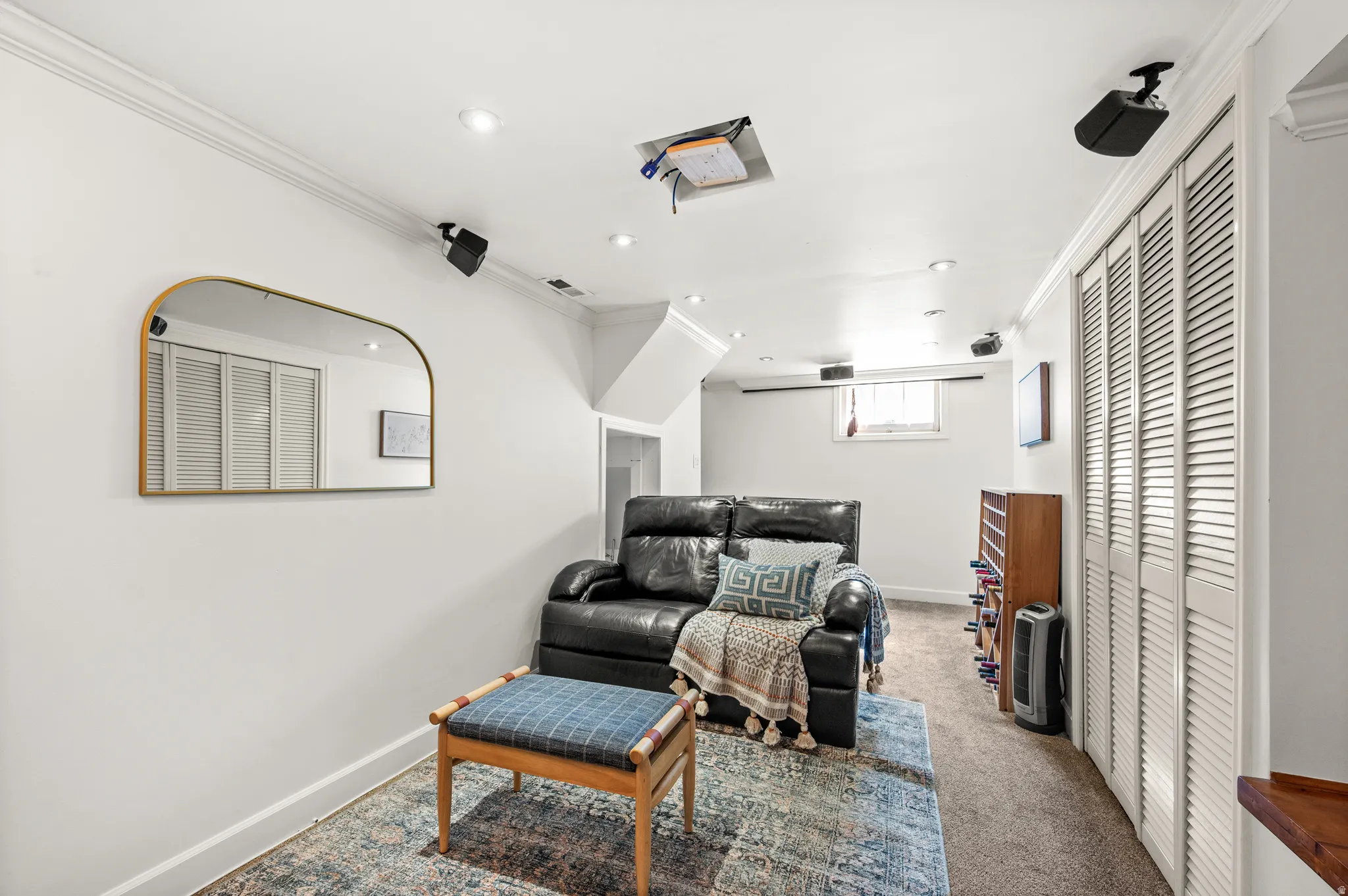 Recreation room featuring recessed lighting, crown molding, wall-mounted speakers, and louvered bi-fold closet doors