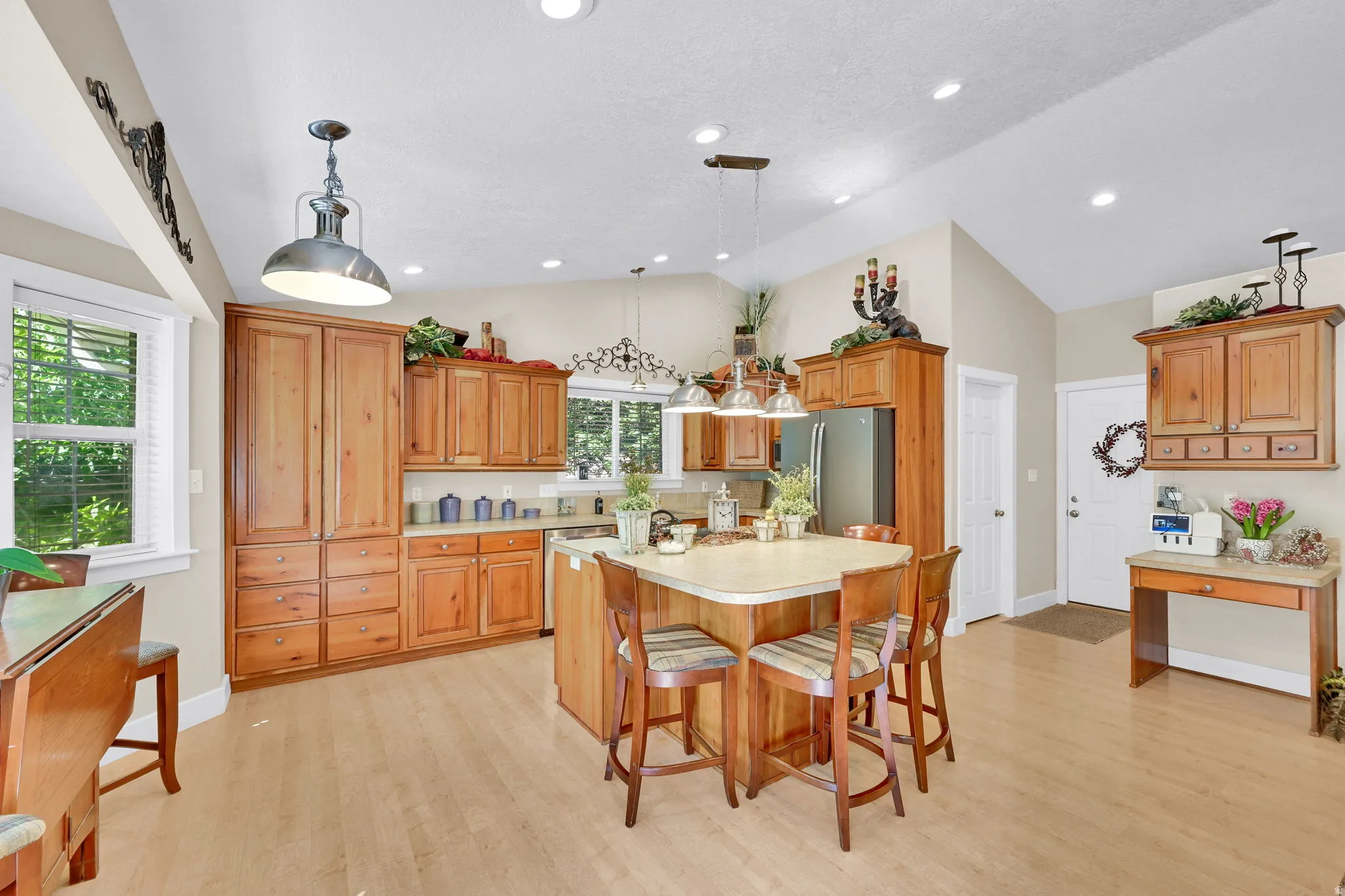 Kitchen featuring a central island with seating, natural wood cabinetry, light-toned flooring, recessed lighting, and a vaulted ceiling