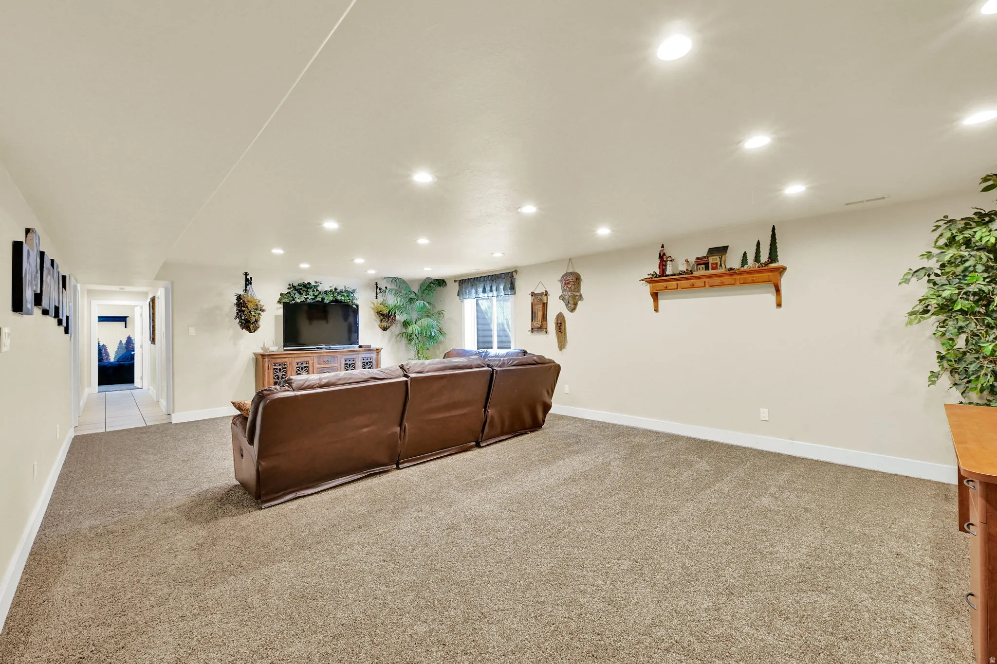 Spacious interior room featuring light-toned walls, recessed lighting, and a textured carpeted floor