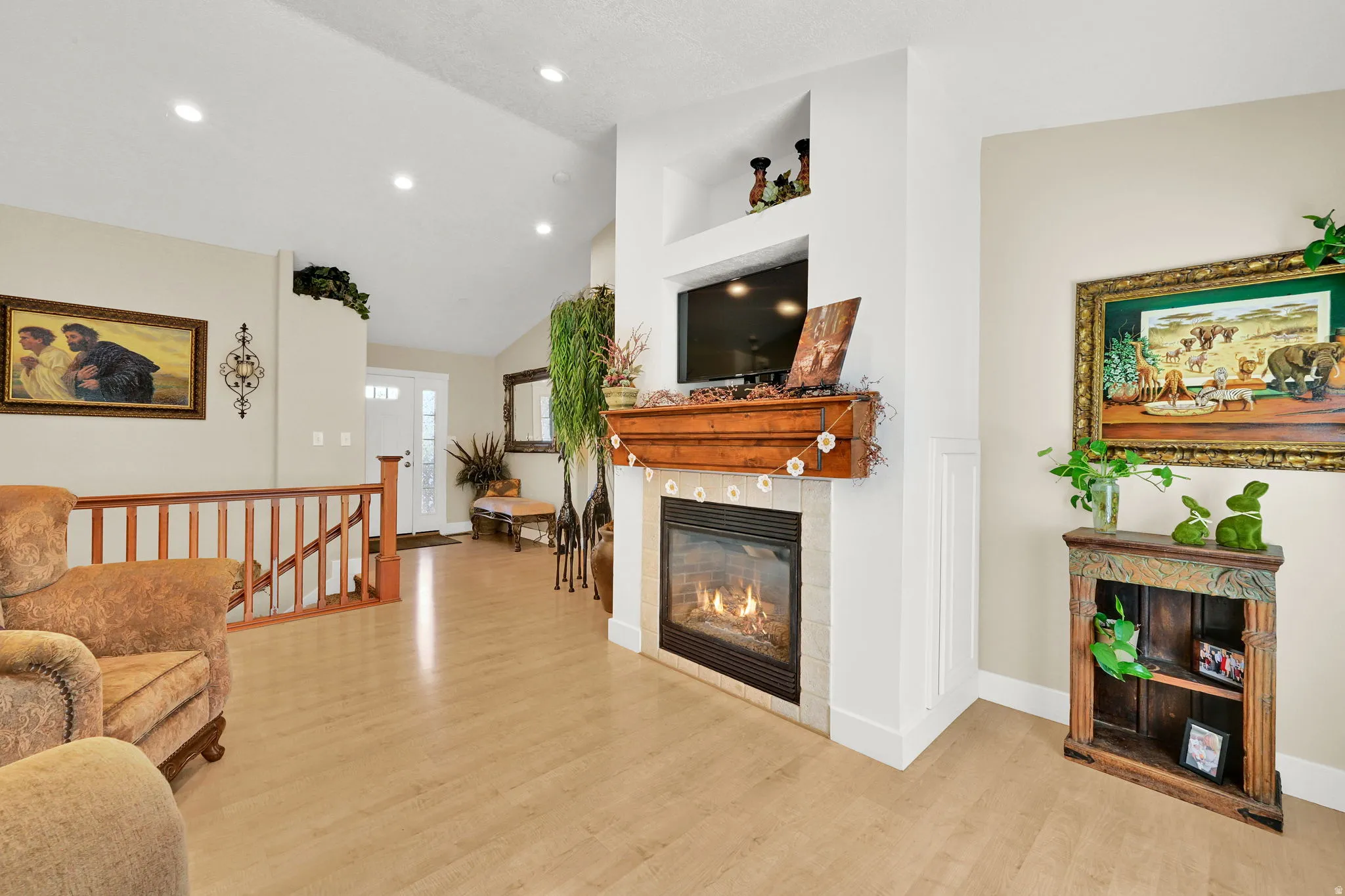Living area featuring a gas fireplace with a wood mantel, light wood-finish flooring, recessed lighting, vaulted ceilings, and a light-toned wall color