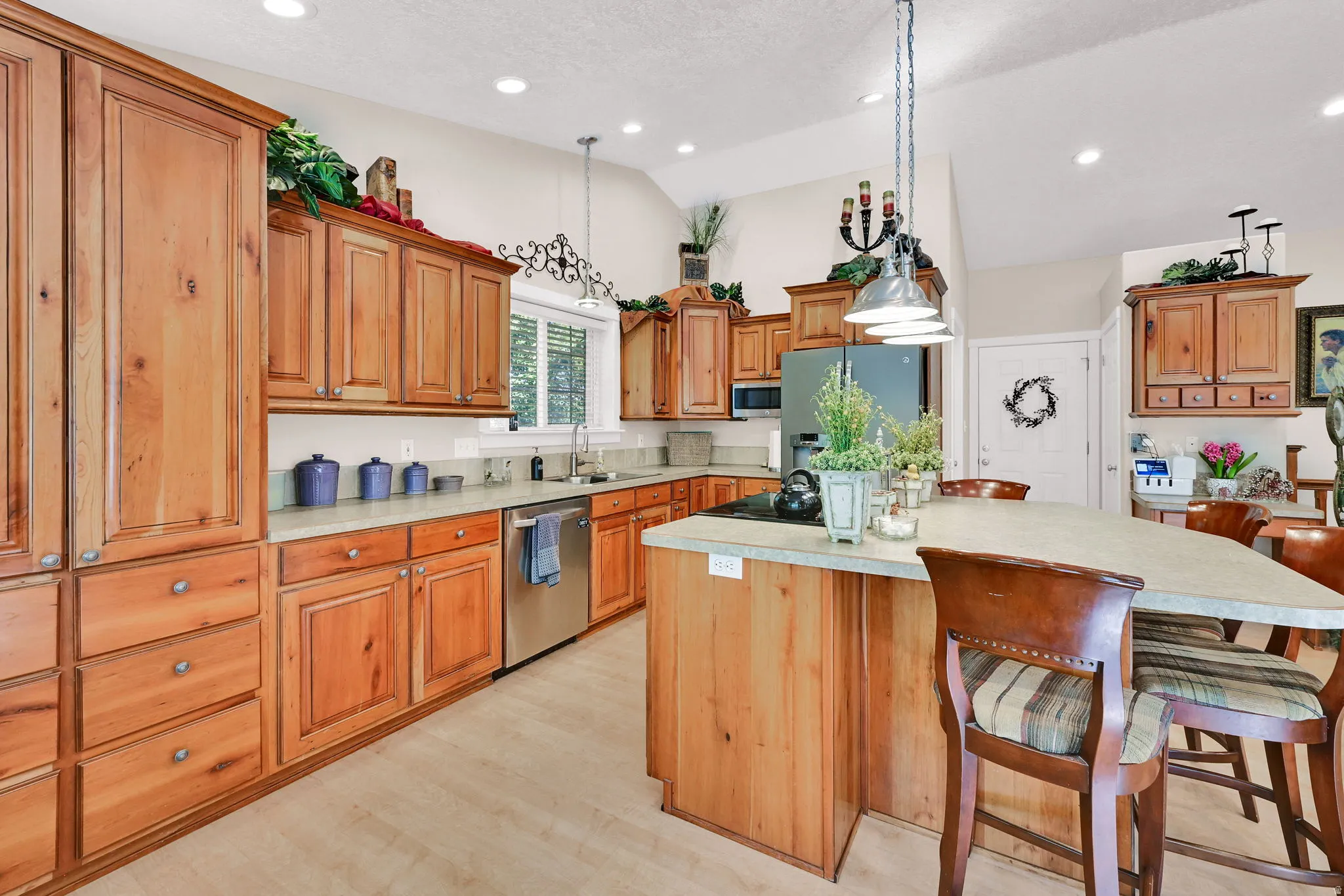 Kitchen featuring extensive wood cabinetry, light-colored countertops, stainless steel appliances, a center island with seating, and recessed lighting