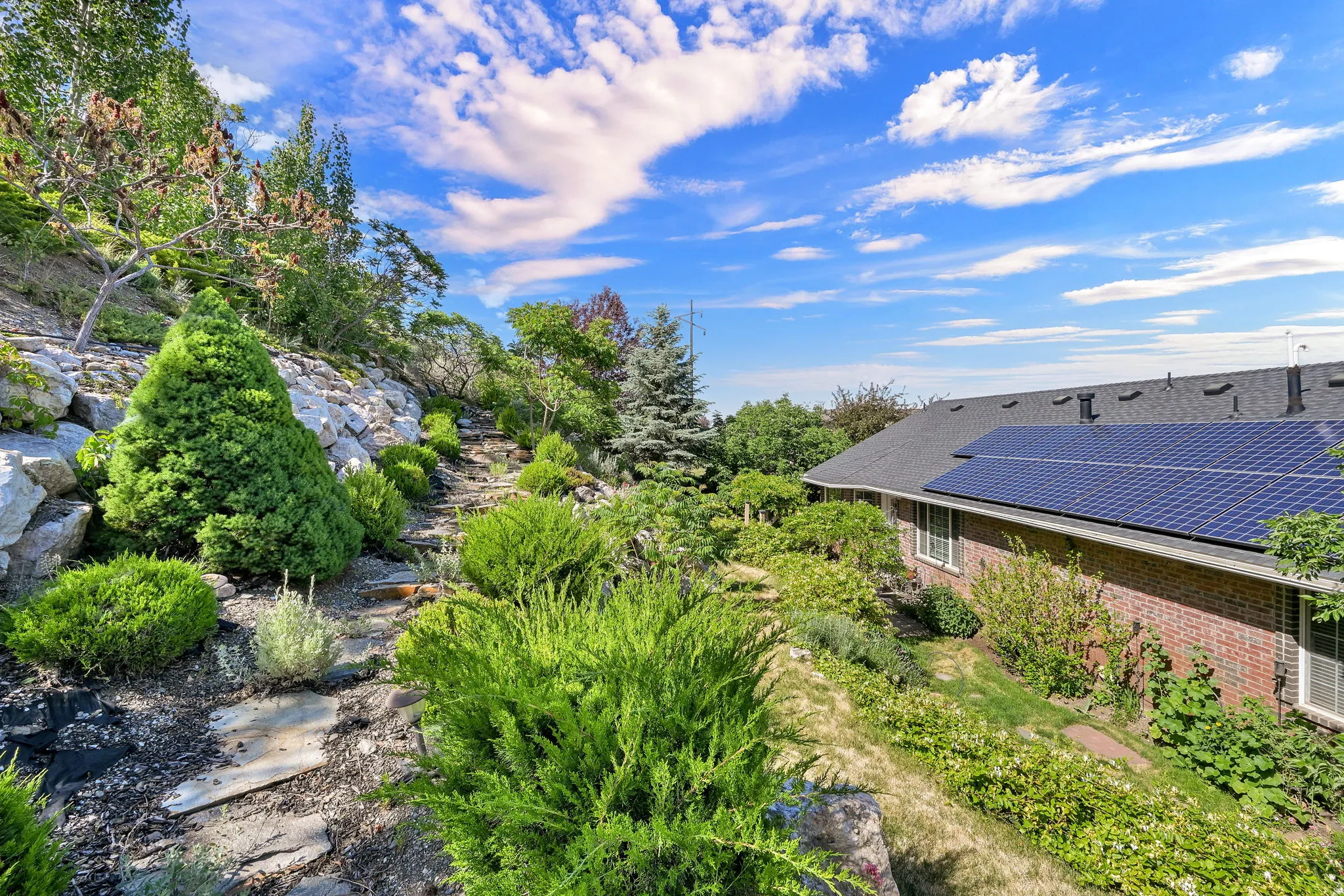 Extensive terraced landscaping featuring a stone pathway, diverse plantings, and mature trees