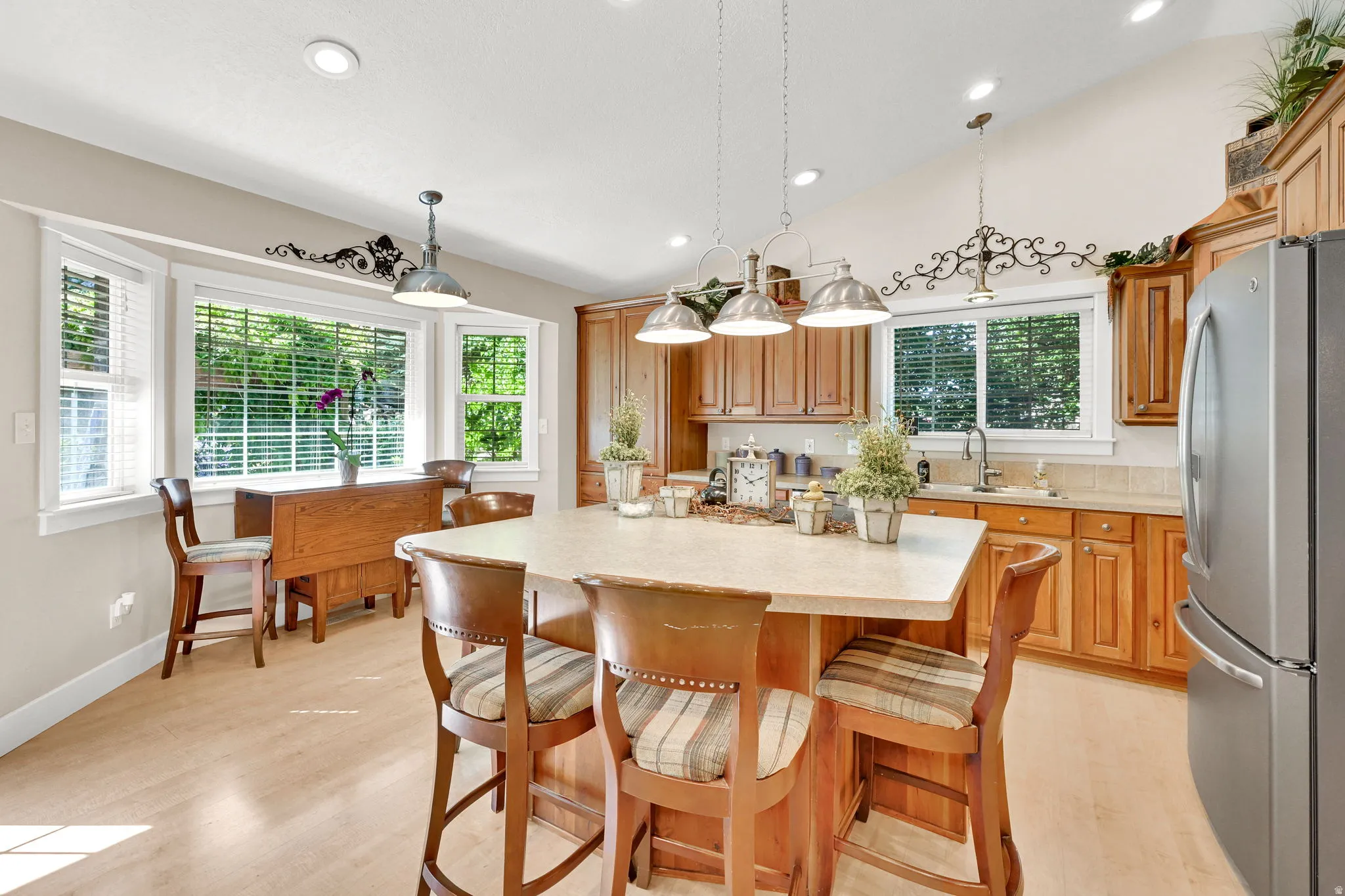 Kitchen featuring a central island with integrated seating, light wood-finish flooring, recessed lighting, and a bay window with blinds