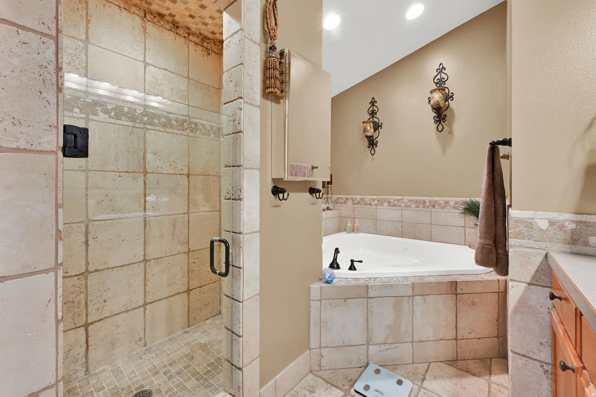 Tiled shower enclosure with glass surround, integrated lighting, and a built-in corner soaking tub with tiled surround