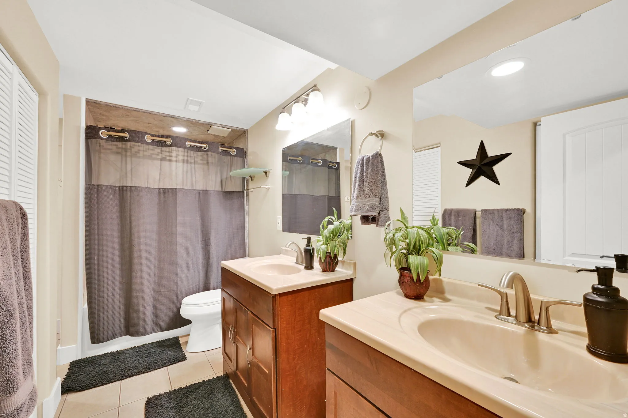 Bathroom featuring dual vanity sinks with light-toned countertops and wood-finish cabinetry