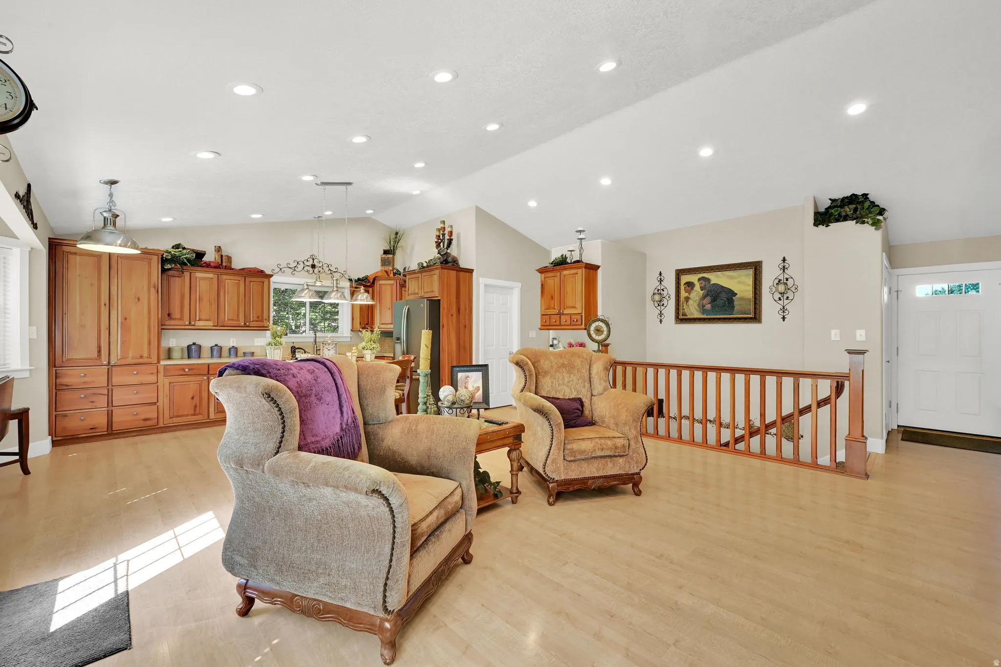 Open concept living area featuring light wood-finish flooring, recessed lighting, and a vaulted ceiling