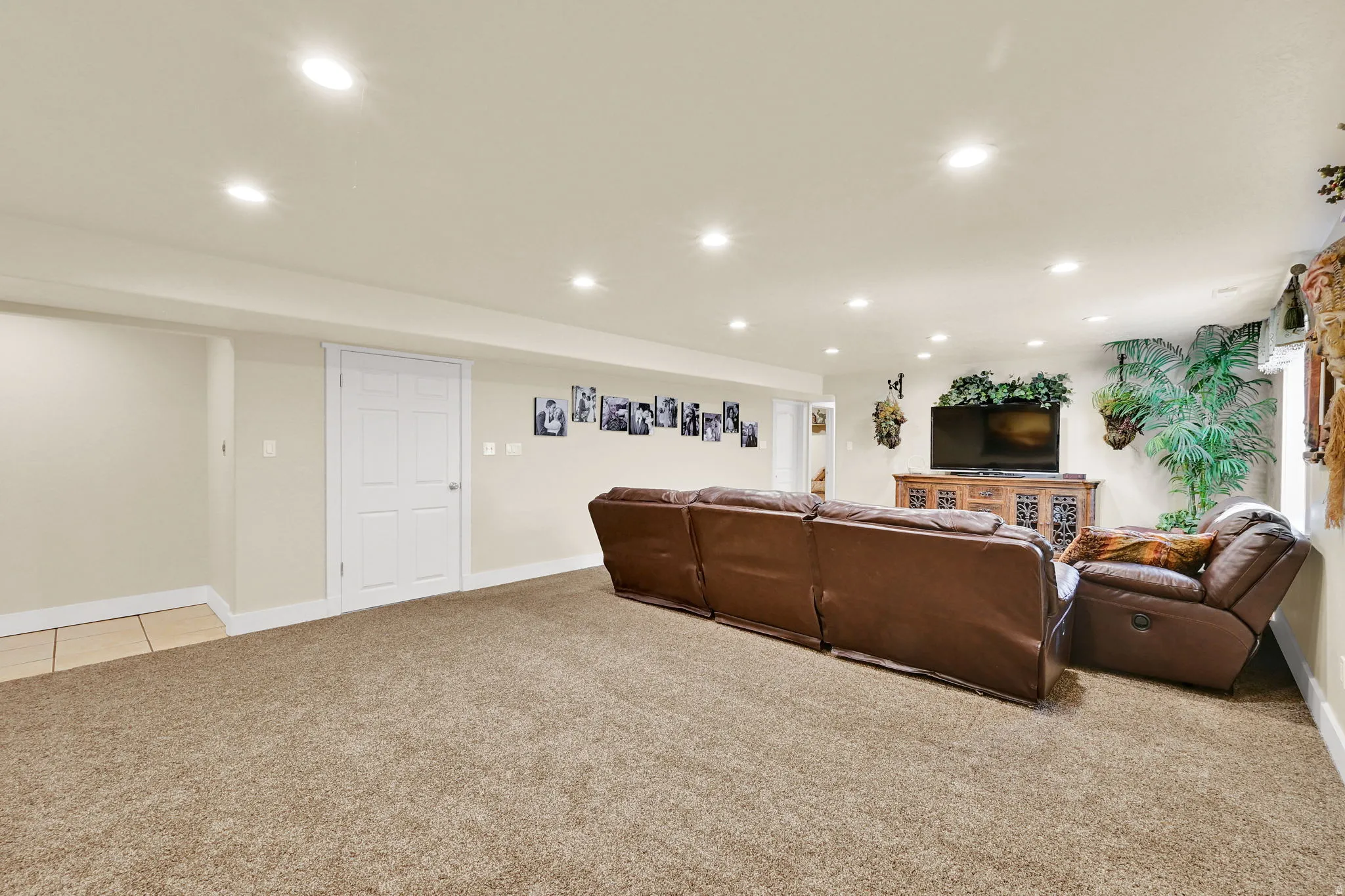 Spacious room featuring neutral carpeting, recessed lighting, white trim, and a paneled interior door
