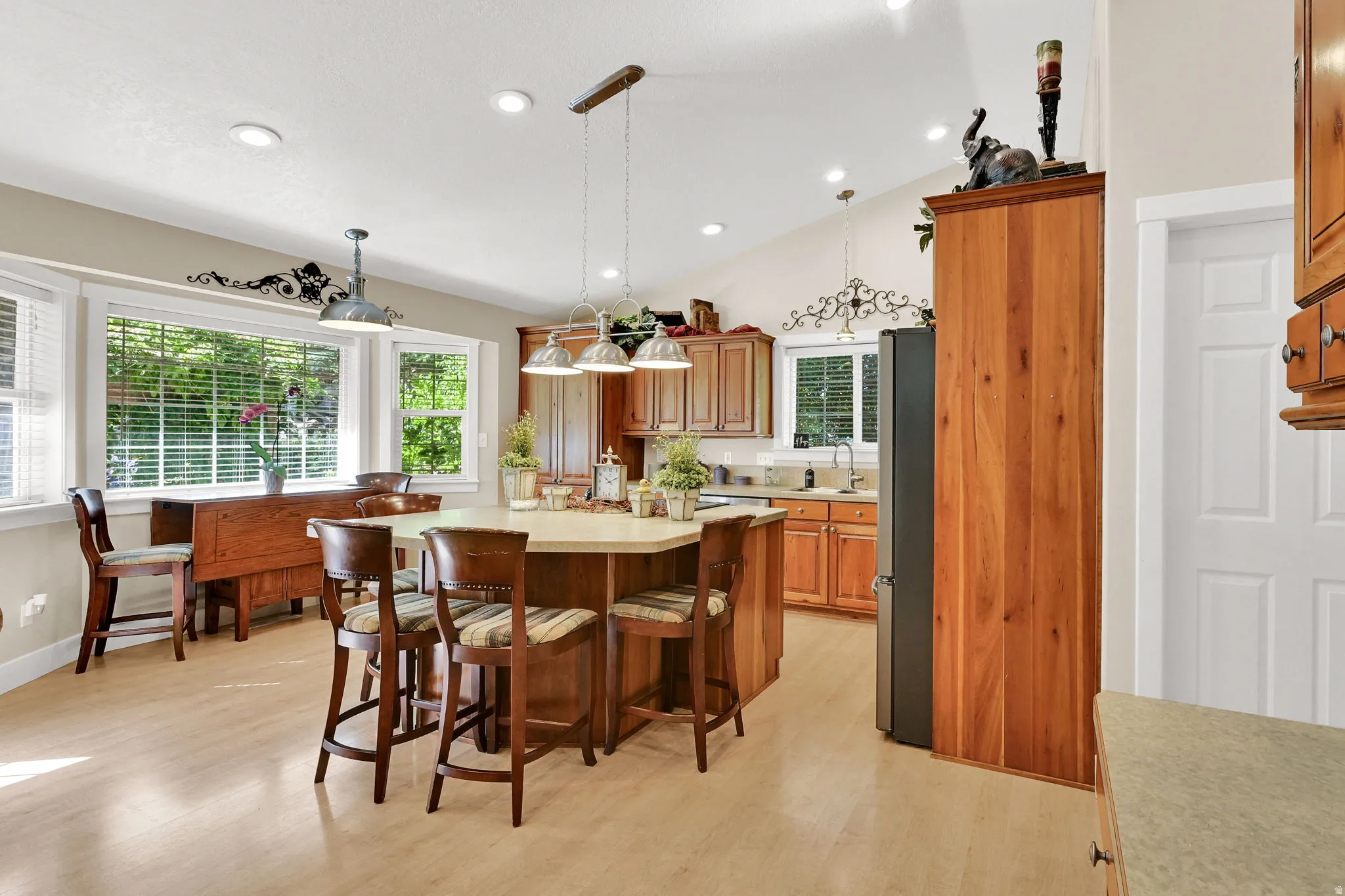 Kitchen featuring a central island with bar seating, wood-finish cabinetry, light-toned countertops, and multiple windows