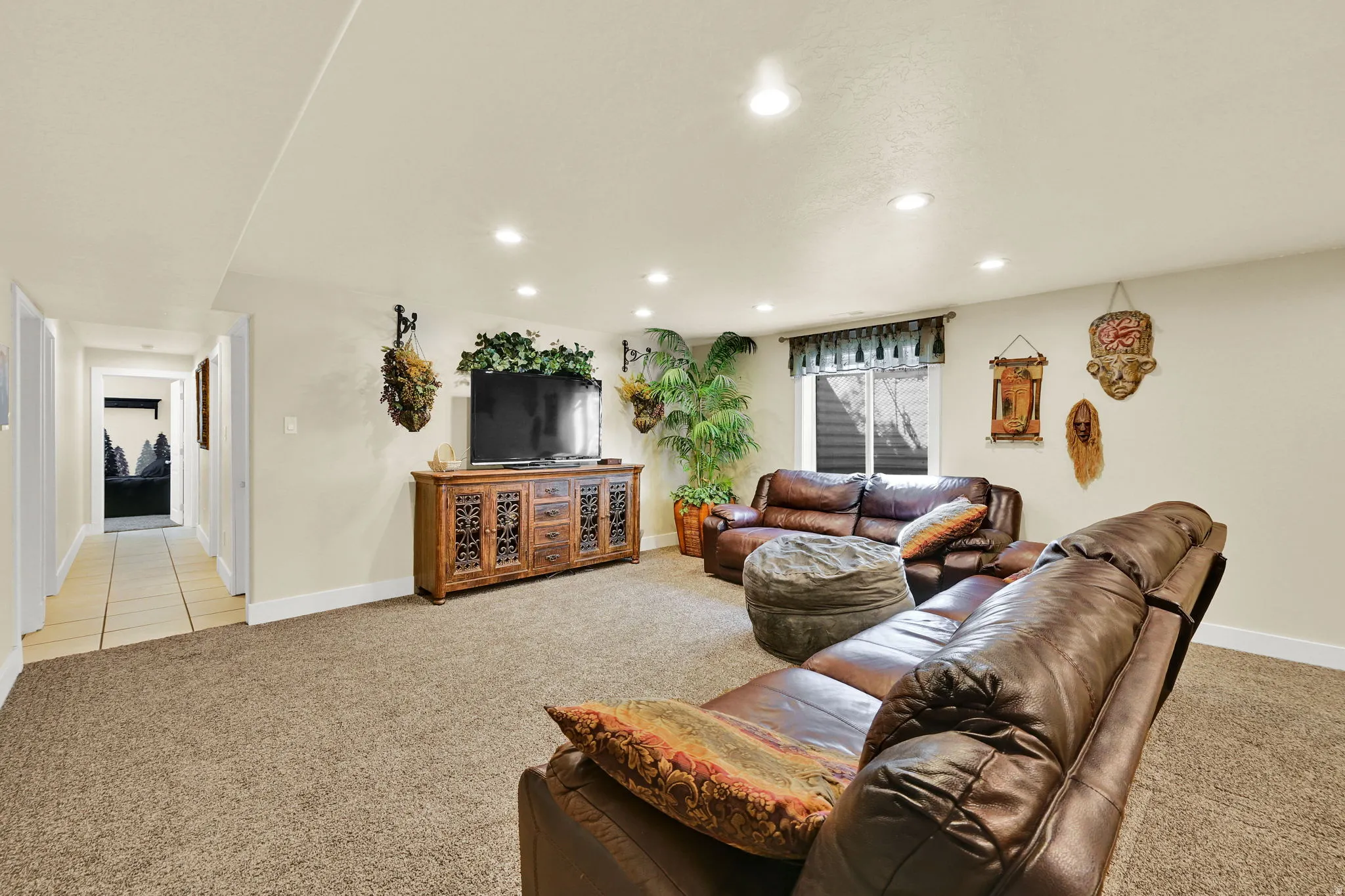 Carpeted living area with recessed lighting and a wood-finish media console
