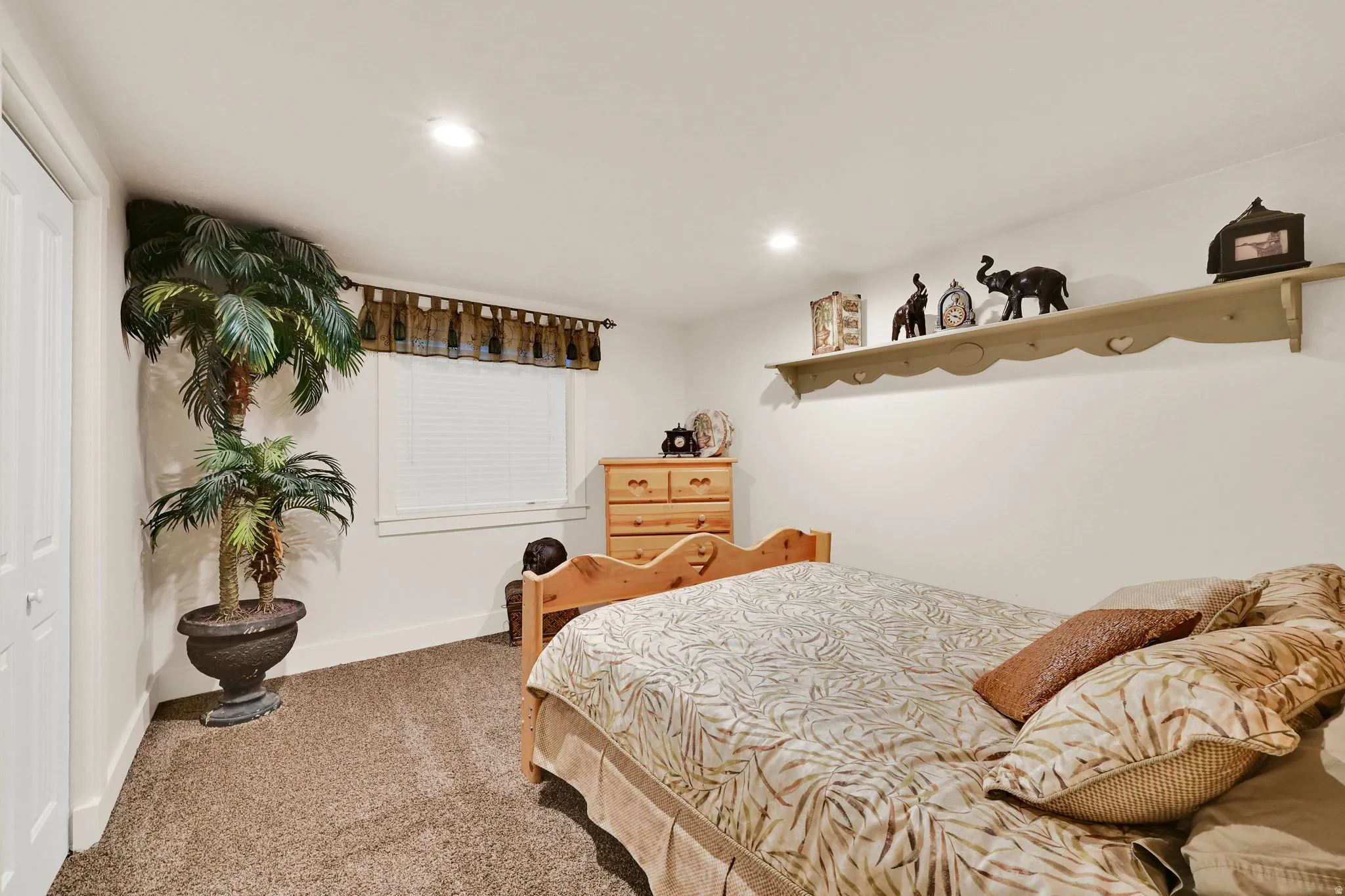 Carpeted room featuring a white window with horizontal blinds, recessed lighting, and a decorative wall shelf