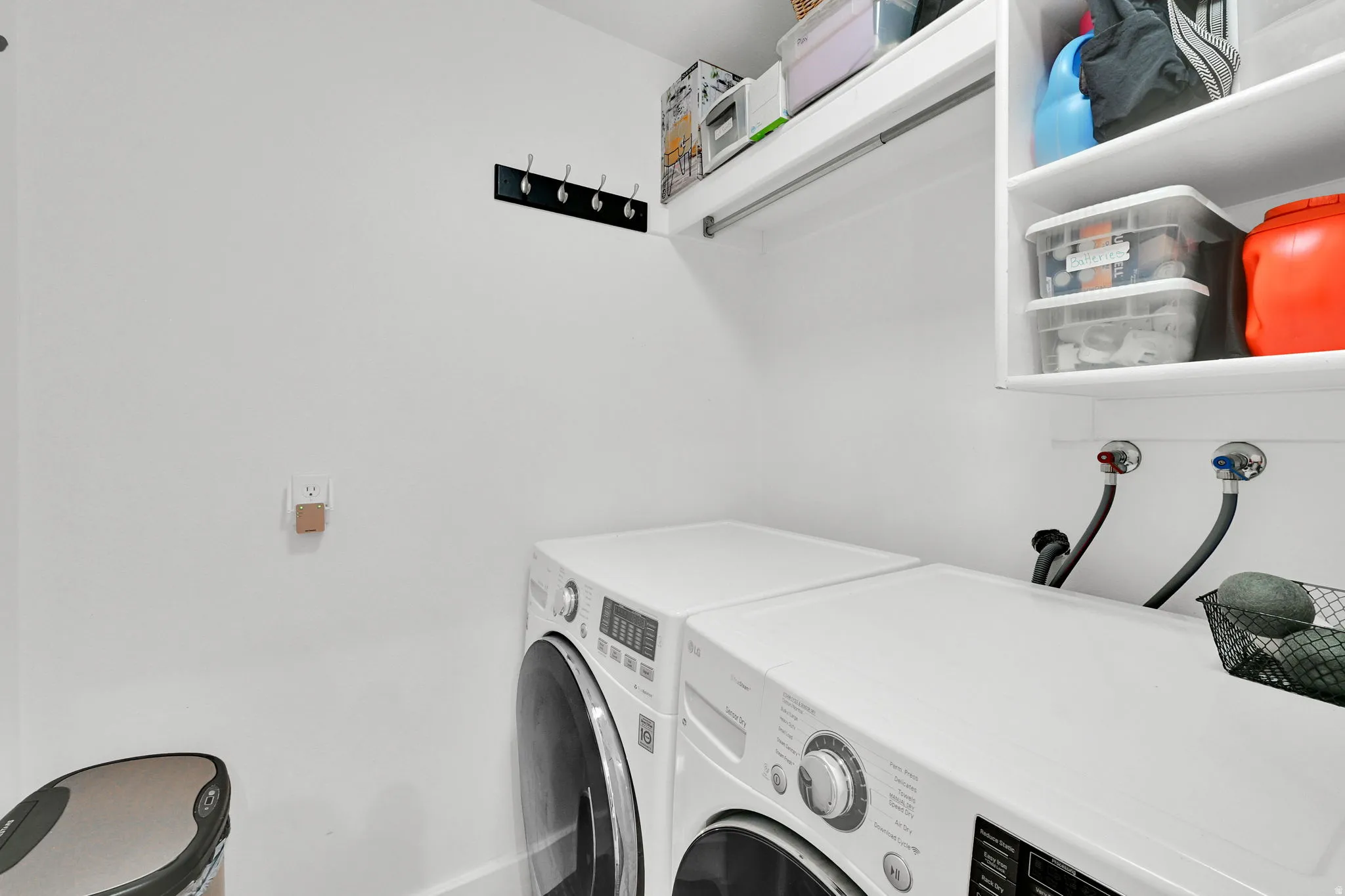 Dedicated laundry area featuring white walls, an upper storage shelf, and a clothing rod